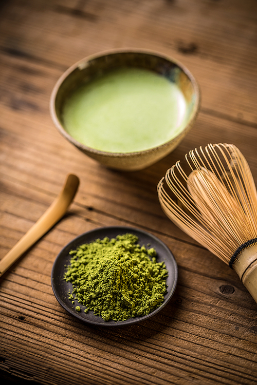 Matcha fine powder and green tea with whisk and spoon
