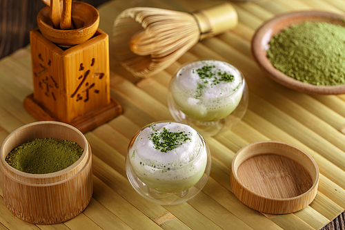 Matcha latte in a glass cup with matcha powder