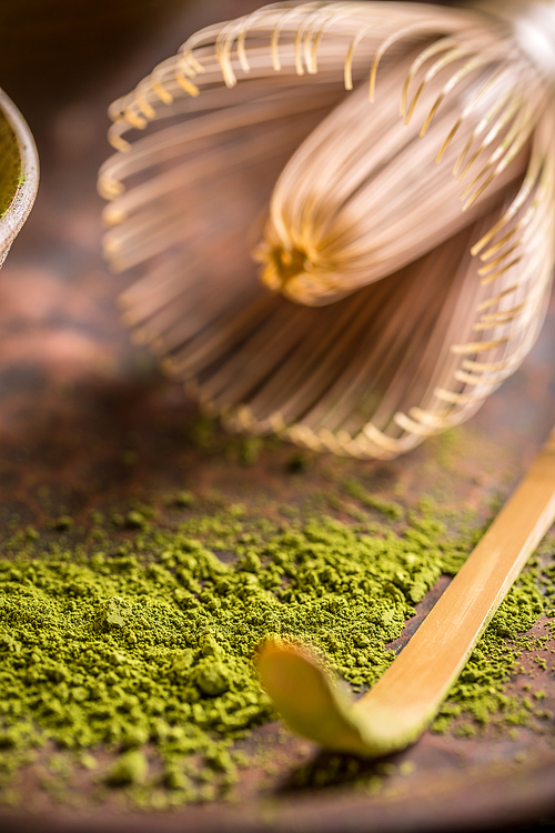 Green tea powder with bamboo whisk and matcha spoon