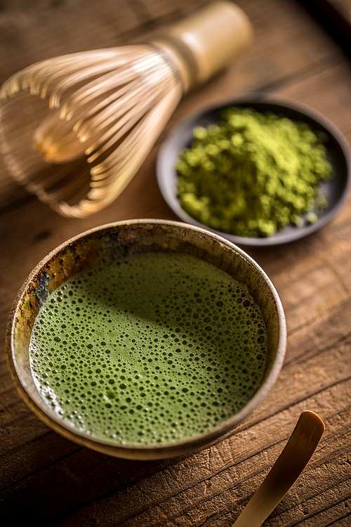 Matcha tea in bowl with bamboo whisk
