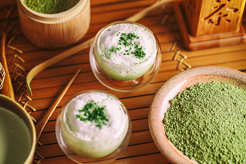 Matcha latte in a glass cup with matcha powder