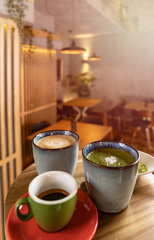 Cups of coffee, espresso and matcha latte on table at a cafe blurred background