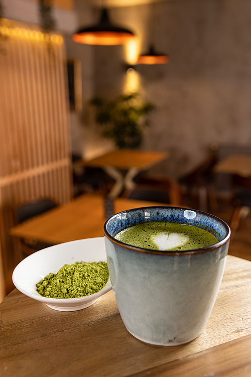 Cup of matcha latte on wood table in cafe, leisure lifestyle concept