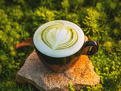 Matcha green tea latte in a black cup.