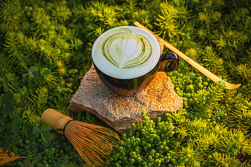 Hot green matcha tea latte with heart pattern