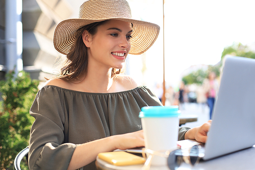 Happy nice woman working on laptop in street cafe