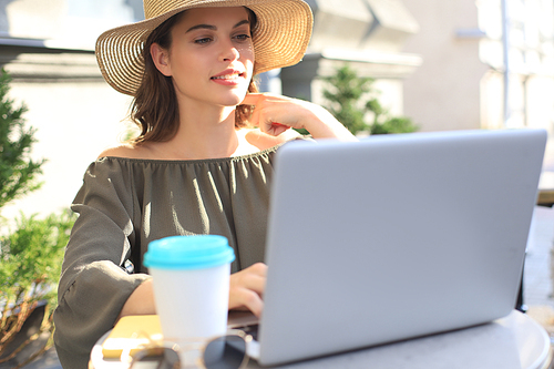 Happy nice woman working on laptop in street cafe