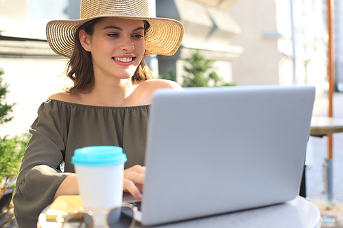 Happy nice woman working on laptop in street cafe