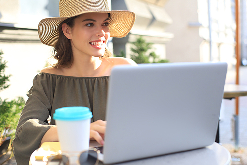 Happy nice woman working on laptop in street cafe