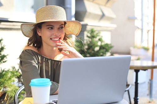 Happy nice woman working on laptop in street cafe