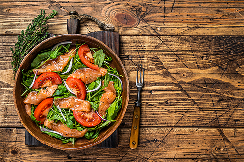 Vegetable salad with smoked salmon, arugula, tomato and green vegetables. wooden background. Top View. Copy space.