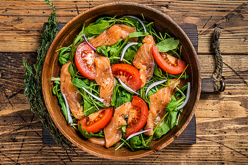 Vegetable salad with smoked salmon, arugula, tomato and green vegetables. wooden background. Top View.