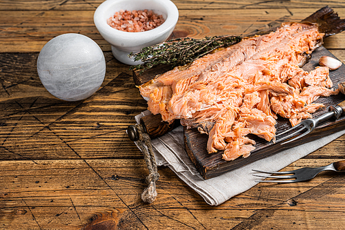 Hot smoked salmon fish fillet on a wooden board. Wooden background. Top view. Copy space.
