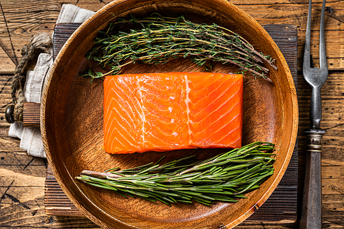Healthy food - fresh salmon fillet steak with herbs. Wooden background. Top view.