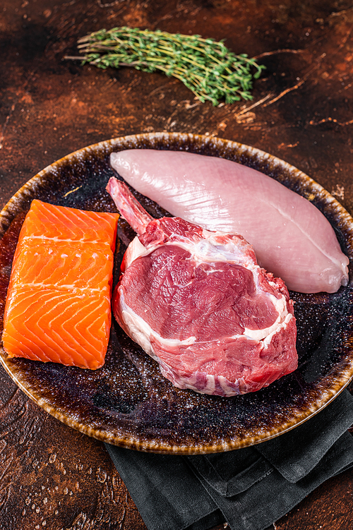 Uncooked raw steaks -fish salmon, beef or veal and turkey breast fillet. Dark background. Top view.
