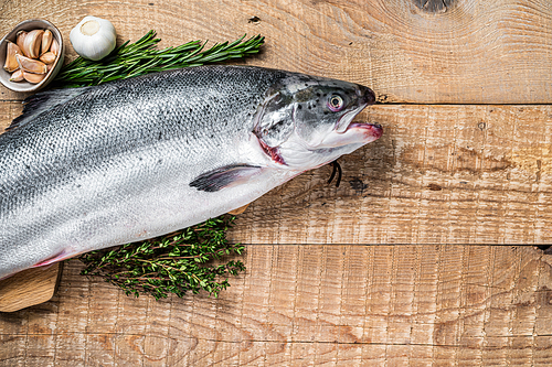 Raw marine salmon fish on a  wooden kichen table with herbs. Wooden background. Top view. Copy space.