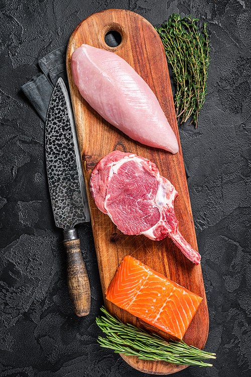 Raw meat steaks - fish salmon, beef veal and turkey. Black background. Top view.