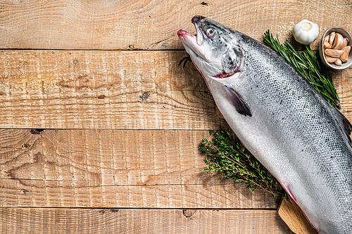 Raw marine salmon fish on a  wooden kichen table with herbs. Wooden background. Top view. Copy space.