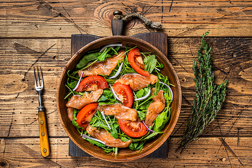 Vegetable salad with smoked salmon, arugula, tomato and green vegetables. wooden background. Top View.