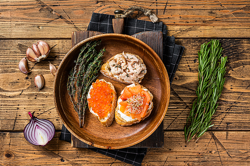 Bruschetta with Hot Smoked salmon, red caviar and herbs. Wooden background. Top view.