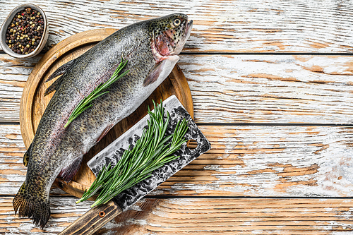 Rainbow trout on an wood board, with rosemary and cleaver. White wooden background. Top view. Copy space.