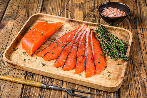 Salted salmon fillet slices in a wooden tray with thyme. wooden background. Top view.