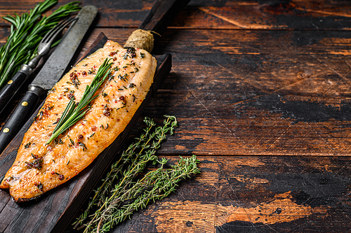 Baked trout fillet on a cutting board. Dark  wooden background. Top view. Copy space.