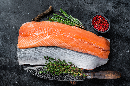 Fresh raw salmon fillet fish on cutting board with knife. Black background. Top view.