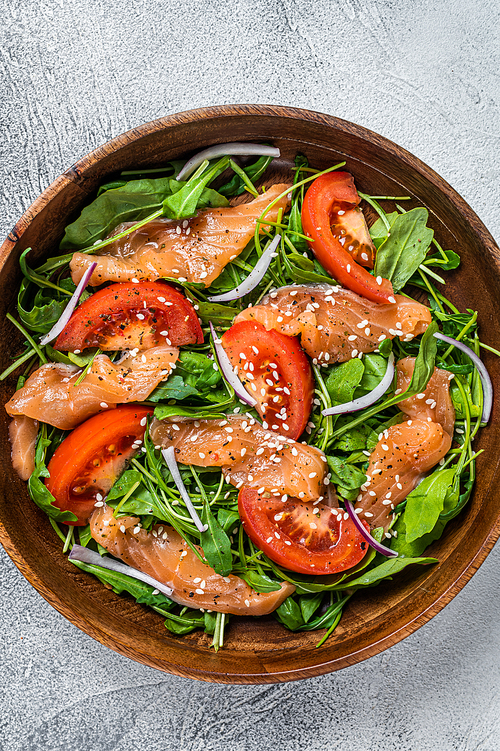 Smoked salmon salad with arugula, tomato and green vegetables. White background. Top View.