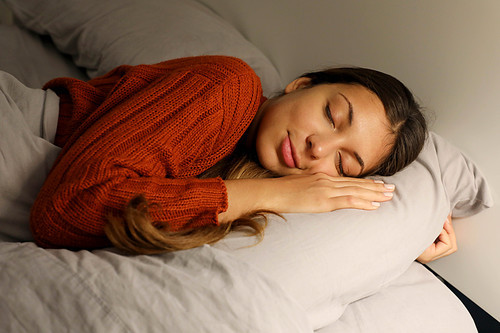 Teenager sleeps hugging pillow on bed at night