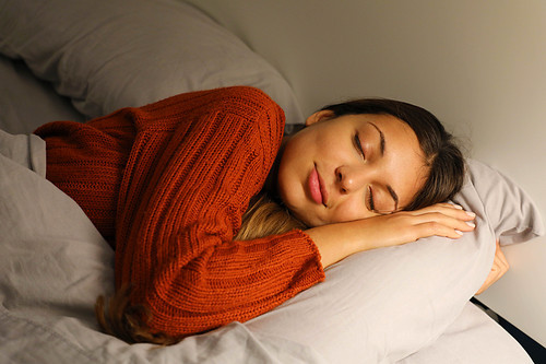 Pretty young woman sleeps hugging pillow on bed at night