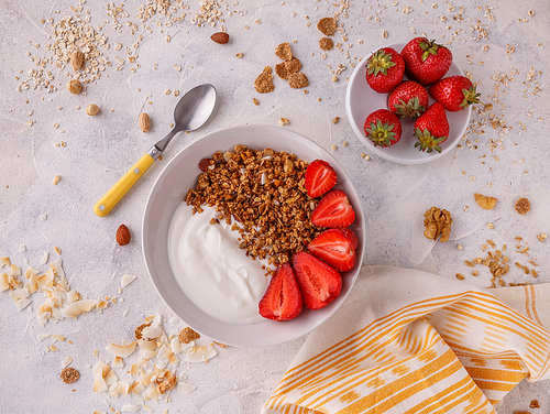 Tasty granola with yogurt and fresh strawberries on white table