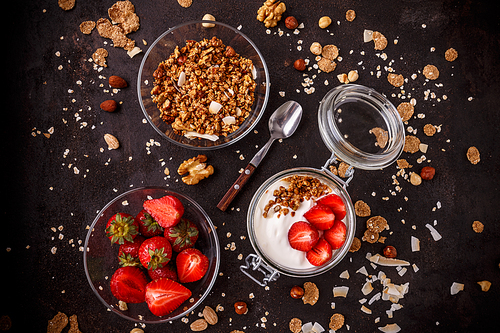 Tasty granola with yogurt and fresh strawberries on black background