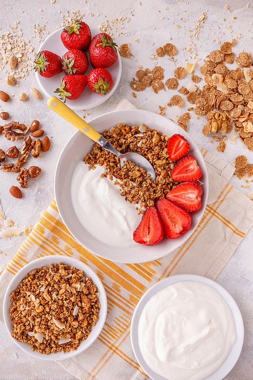 Oat granola breakfast cereal served with yogurt and fresh strawberries