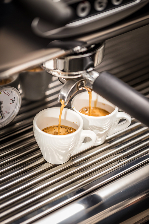 Espresso machine pouring coffee in white cups