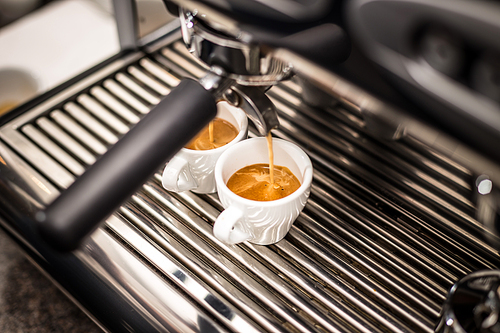 Professional espresso machine pouring fresh coffee into a ceramic cup