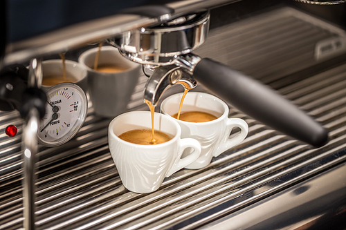 Professional espresso machine pouring fresh coffee into a ceramic cup