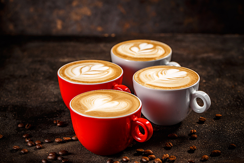 Cups of coffee on dark background with beautiful latte art