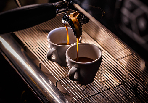 Espresso machine pouring coffee in white cups