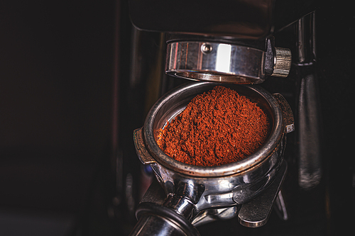 Grinding coffee on professional grinder machine in coffeeshop, close up