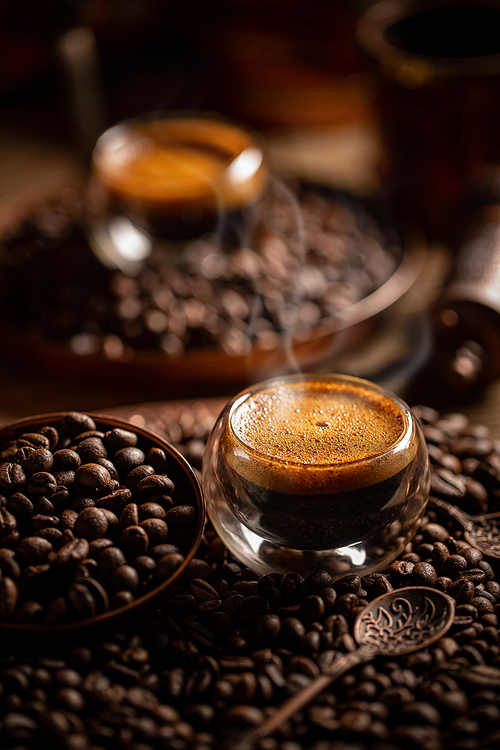 Espresso in double walled glass cup on roasted coffee beans background