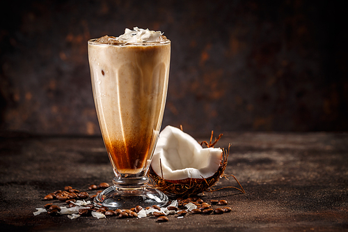 Glass of tasty coconut flavored coffee on vintage dark background