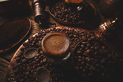 Espresso in a cup of double-sided glass, beside scattered coffee beans