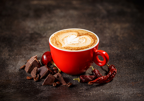 Coffee cup with chili peppers and chocolate on a dark vintage background