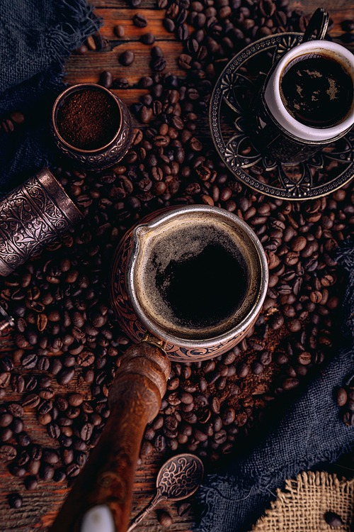 Turkish coffee in a copper Turks and grains are scattered on the wooden surface