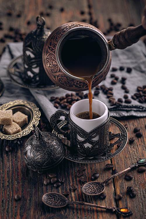 Pouring turkish coffee into traditional embossed metal cup