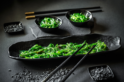 A dish of pickled spicy seaweed on black background