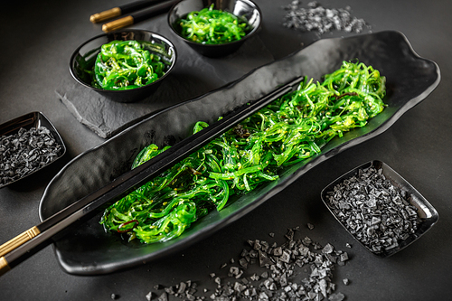 Wakame seaweed salad served on traditional Japanese food on black ceramic dish