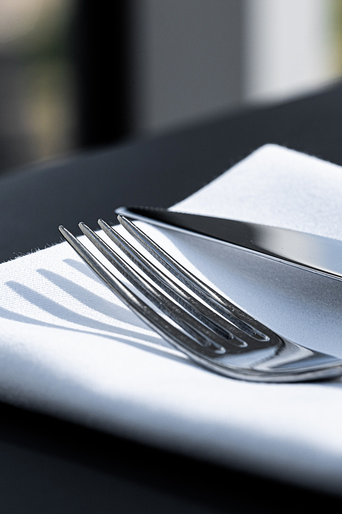 Fork and knife with white napkin on table in luxury restaurant outdoors, fine dining menu for wedding or event and food catering service concept.