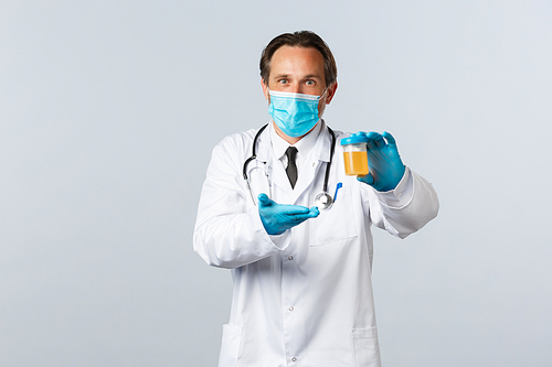 Covid-19, preventing virus, healthcare workers and vaccination concept. Excited lab clinic doctor in medical mask and gloves showing urine sample with satisfied expression, white background.